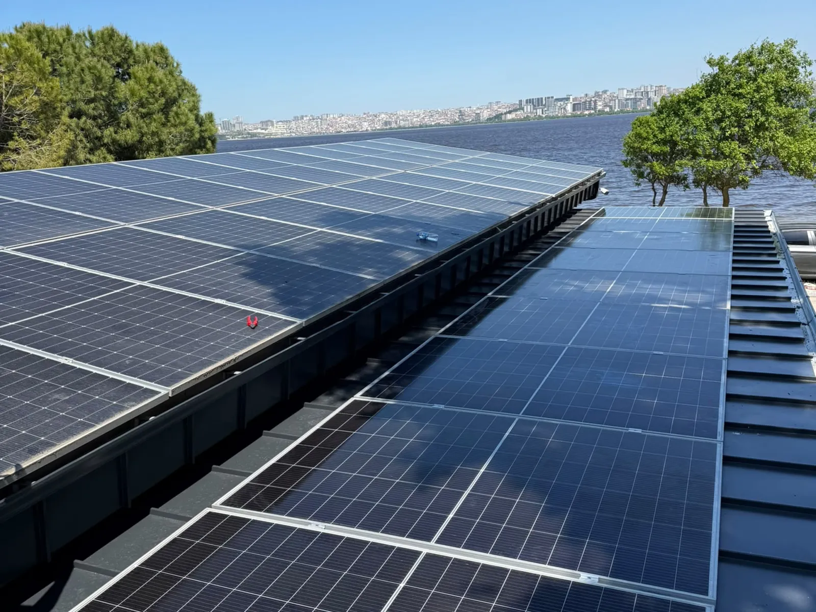 Acoperiș lung acoperit cu panouri solare, pe malul apei